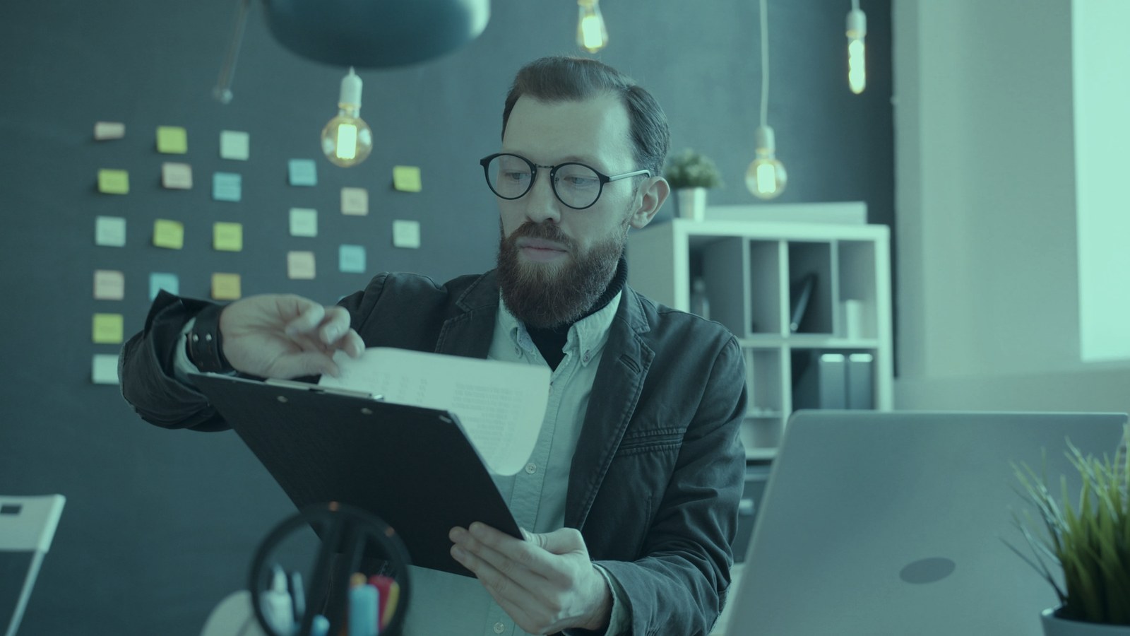 AI governance skills: a man in glasses reviewing papers on a clipboard at his office desk