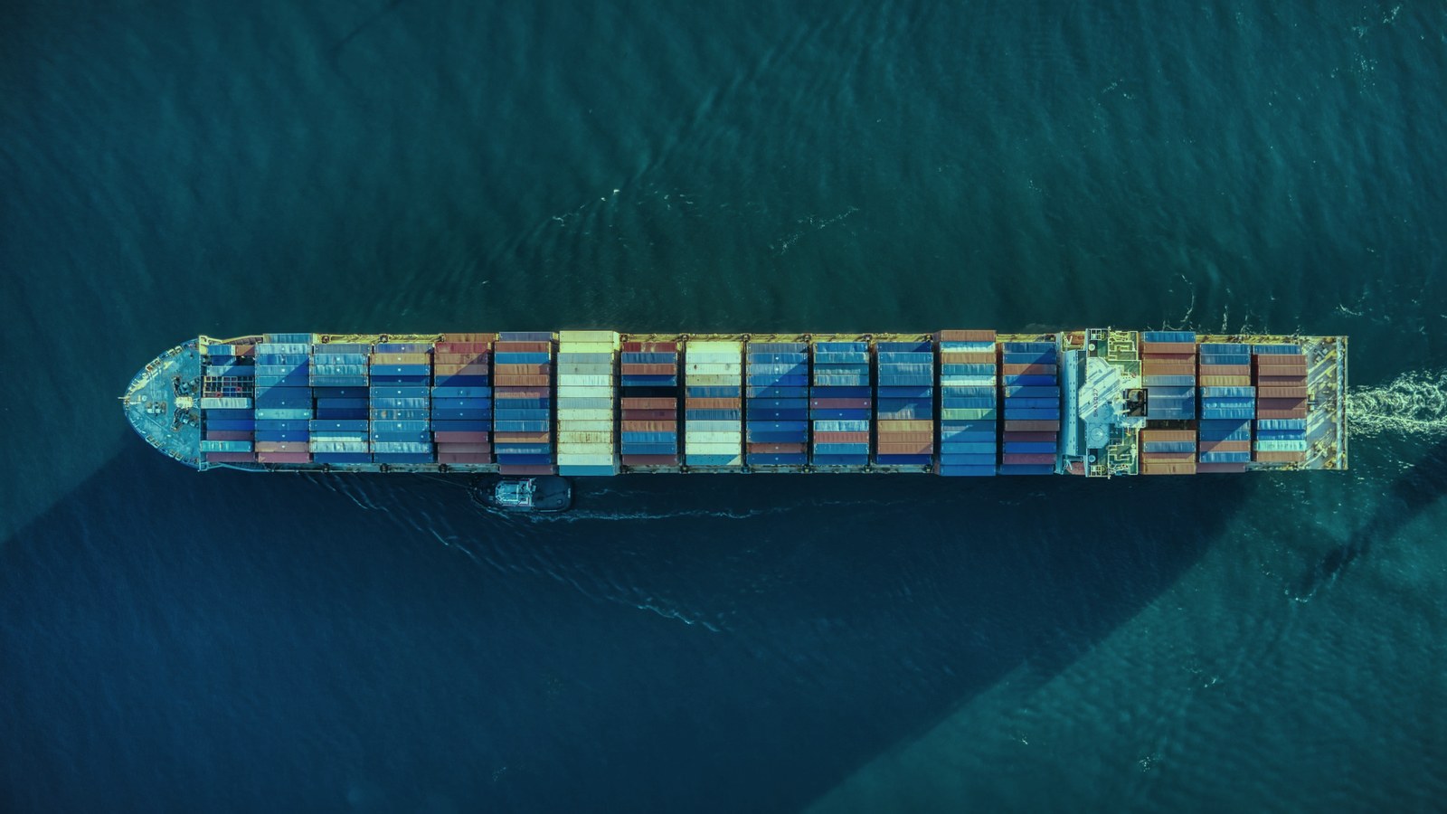 Fractional AI leader cover, a laden container ship crossing open water from above, Axial Search